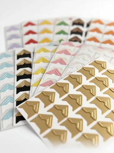 Sheets of premium gold, black, and white self-adhesive photo corners.